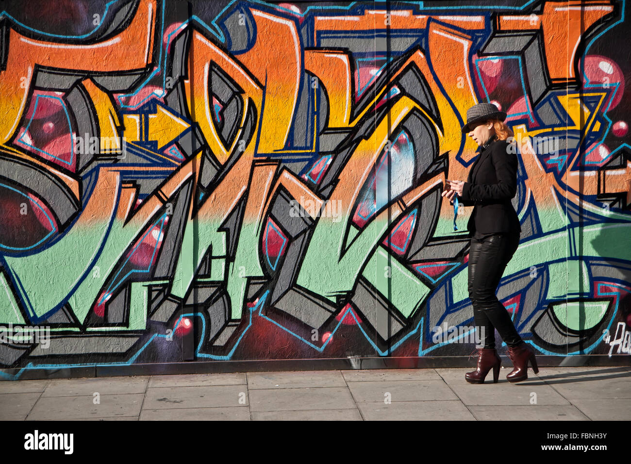 Frau zu Fuß vor Stil Graffiti Wanddekoration, Borough Road, London. Stockfoto