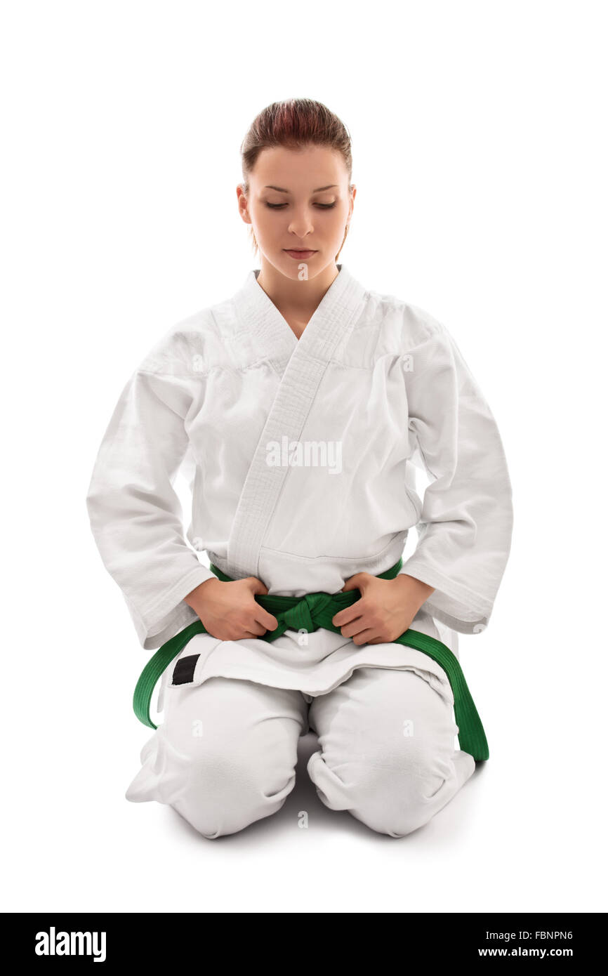 Schöne weibliche Martial Arts Kämpfer in einem weißen Kimono mit grünen Gürtel im Seiza Position unten schauend, auf weißem Hintergrund. Stockfoto