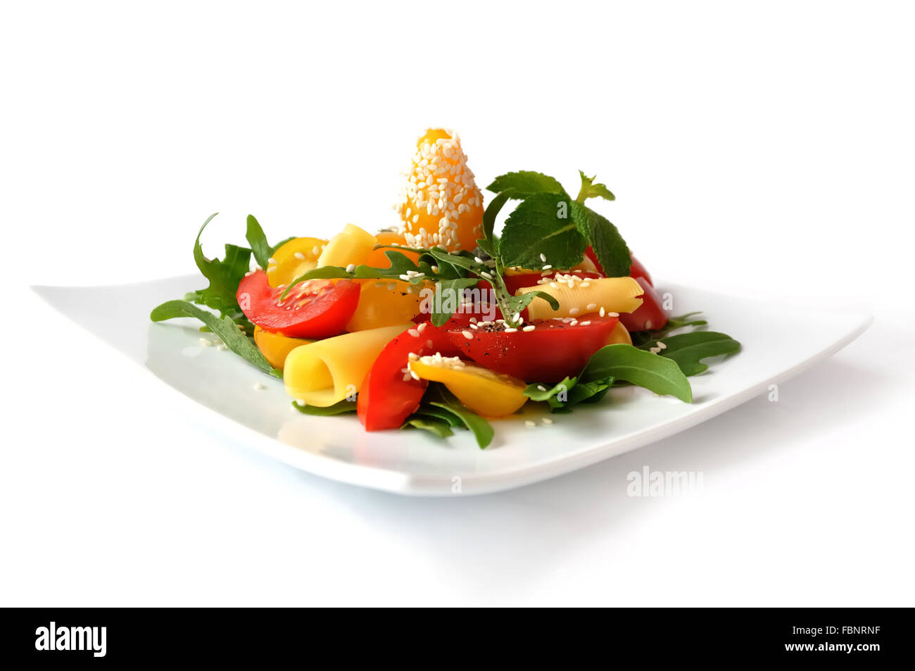 Salat von roten und gelben Tomaten mit Käse, Rucola, Sesam Stockfoto