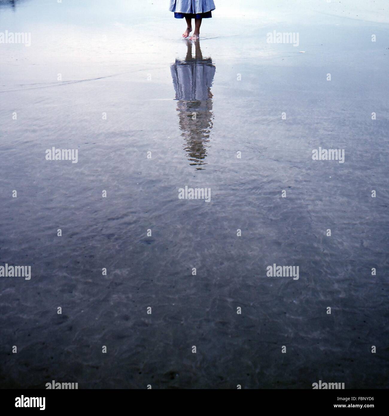 Geringer Teil der Frau zu Fuß auf dem Wasser mit Reflexion Stockfoto