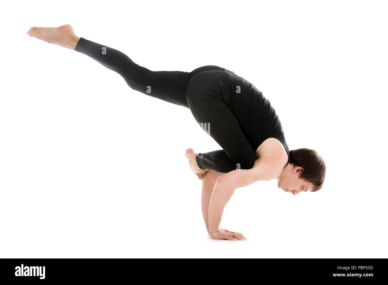 Sportlicher junger Mann tun Yoga, Pilates, Fitness-training, Asana Eka Pada Galavasana Flying Pigeon (fliegenden Krähe) Pose, auf einem Bein Stockfoto