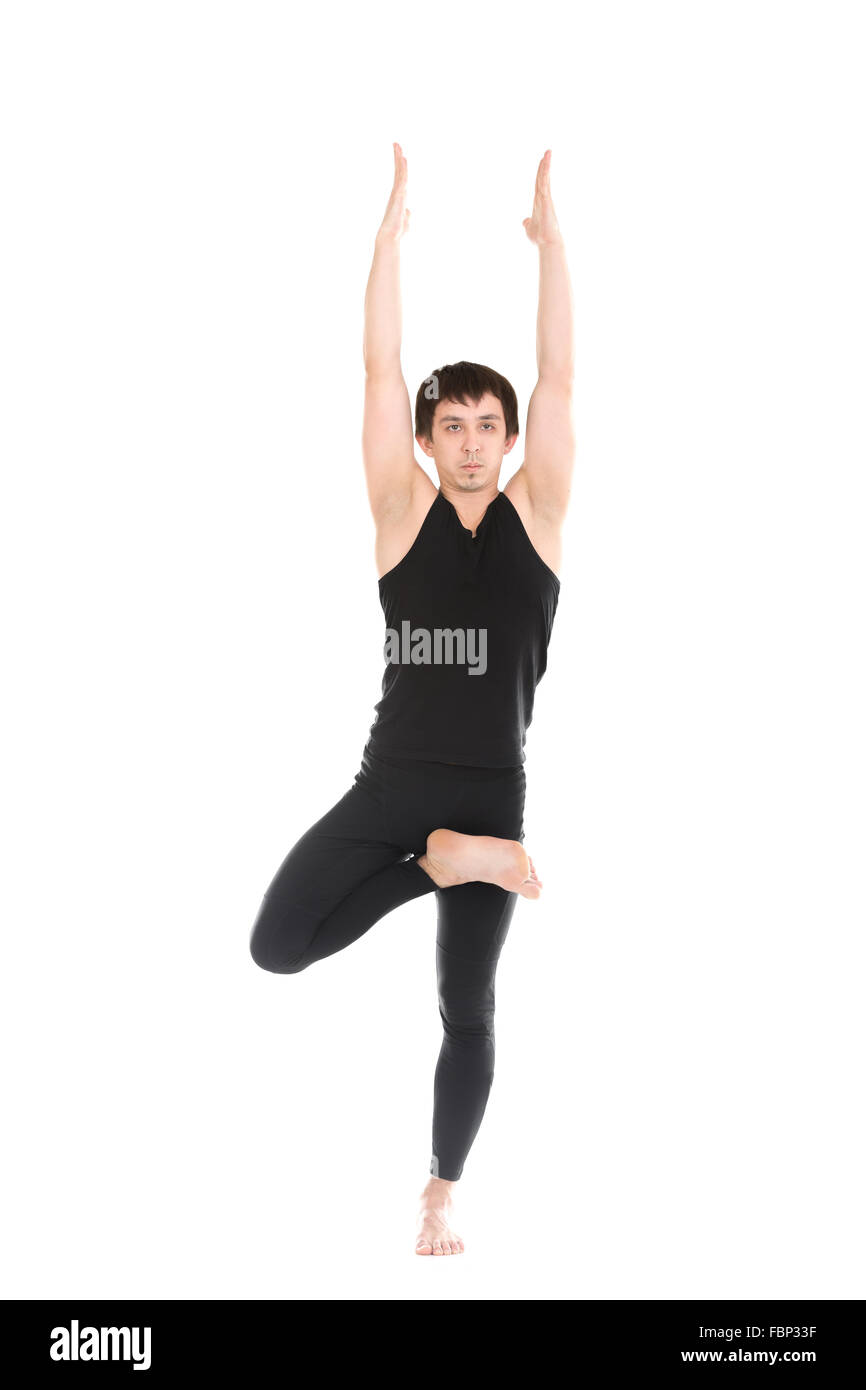 Sportlicher junger Mann beim Yoga, Pilates, Fitness-training, Übungen für die Wirbelsäule, stehend im Baum darstellen, Asana Vrikshasana, Vriksasana Stockfoto