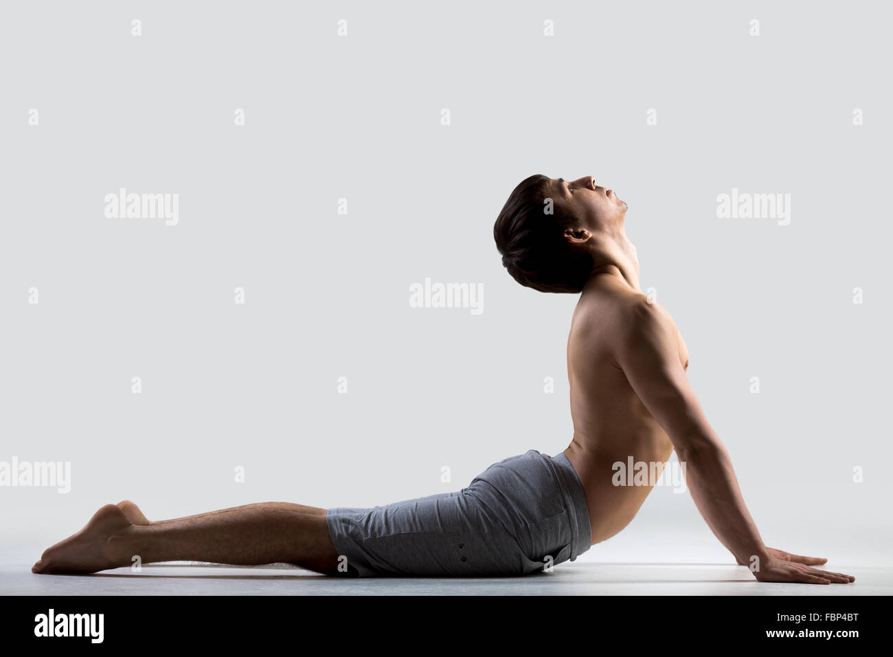 Profil von sportlichen jungen Mann trainieren, Übungen für flexible Wirbelsäule, Bhudjangasana (Bhujangasana oder Cobra darstellen) Stockfoto