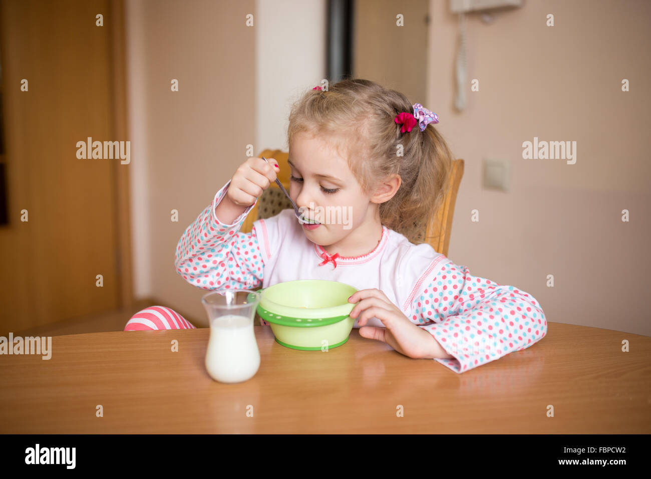 Kleines Mädchen zu Hause frühstücken. Milch-Schnurrbart Stockfoto