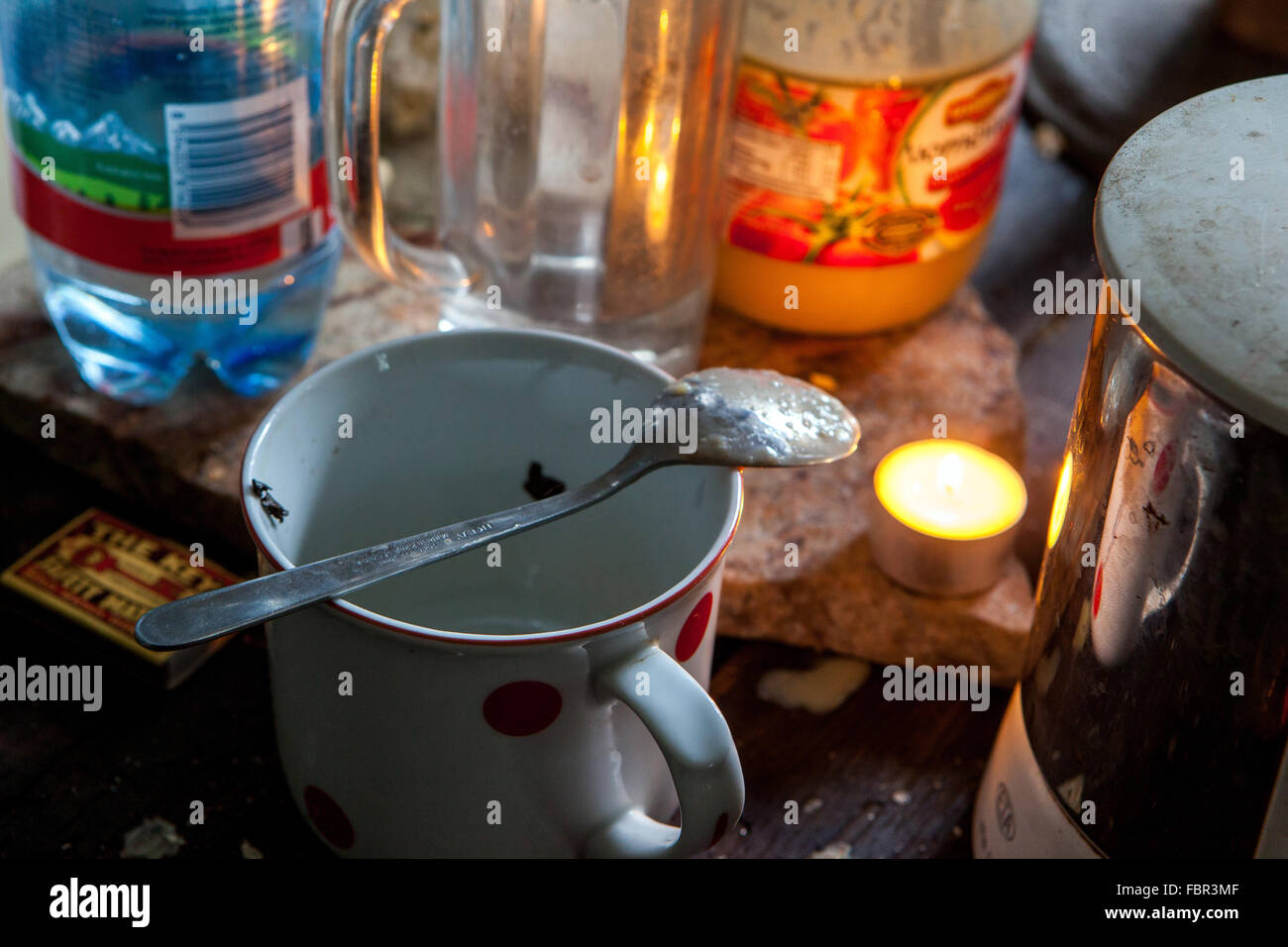 ungewaschenen Polka Dots Kaffee Tasse mit einem Löffel und Flaschen und brennende Kerze Stockfoto
