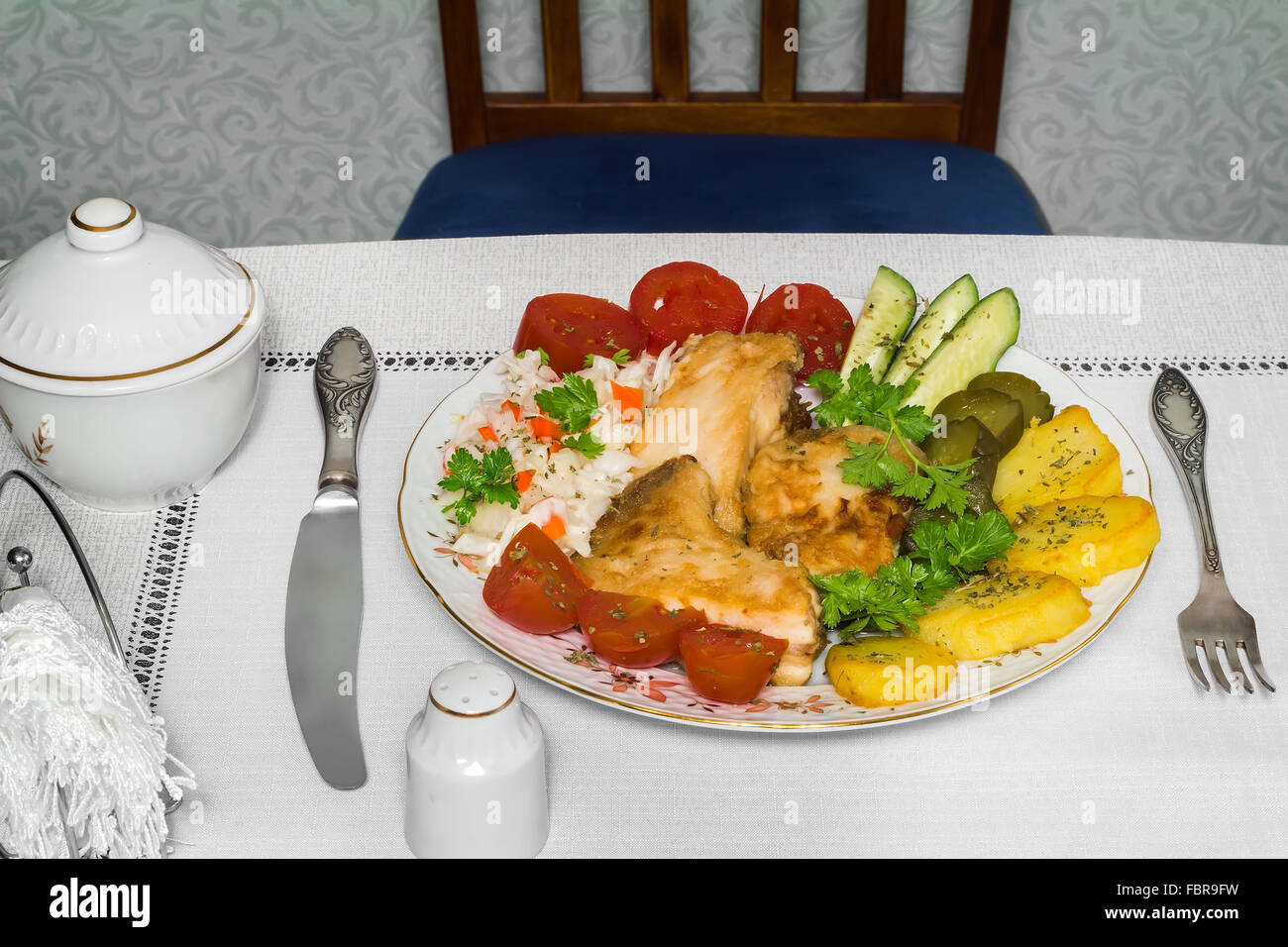 Auf dem Tisch ist eine Platte mit Stücken von lecker gebratenen Fisch und verschiedenen Basimi. Stockfoto
