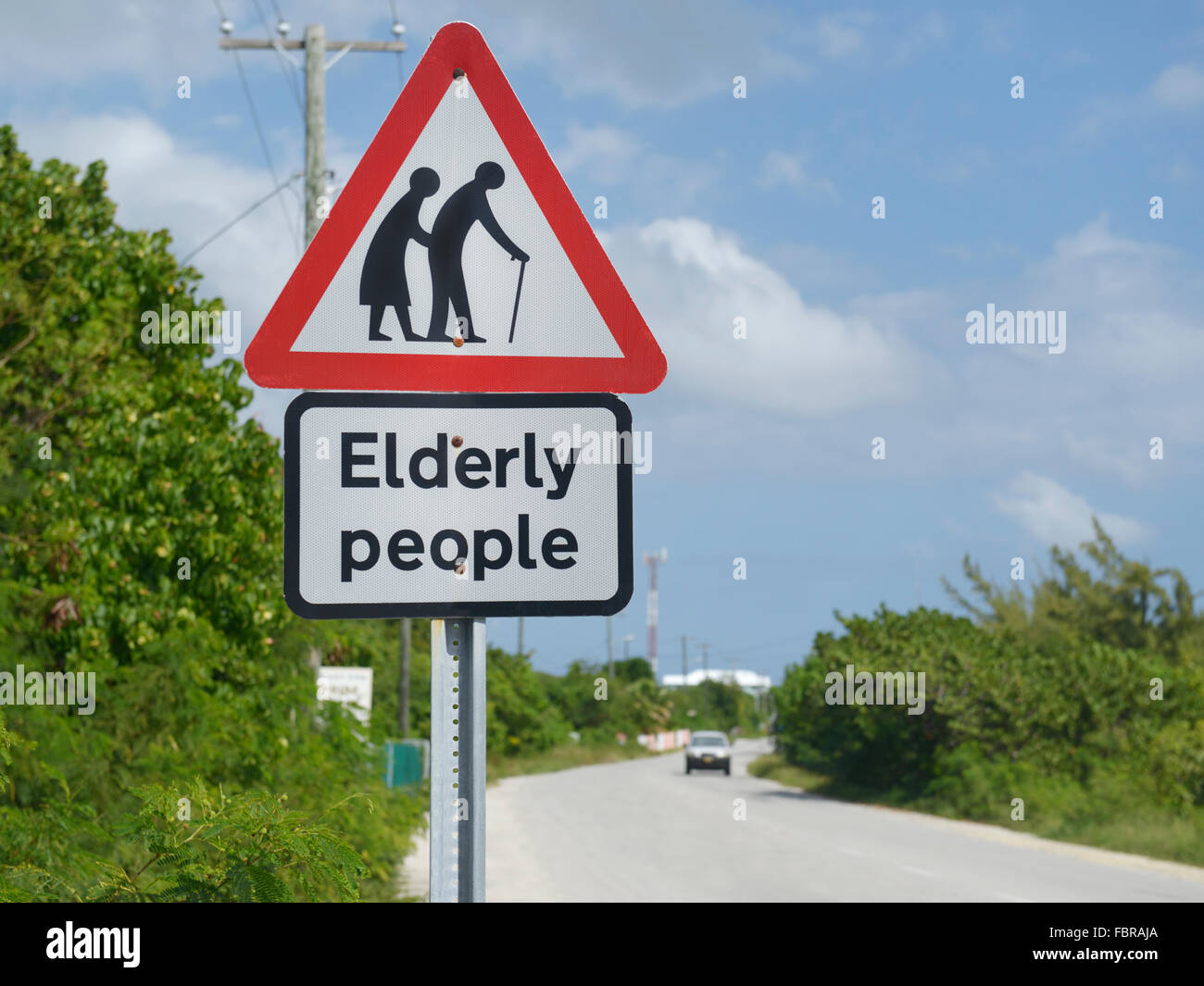 Schild warnt über ältere Menschen überqueren einer Straße Stockfoto