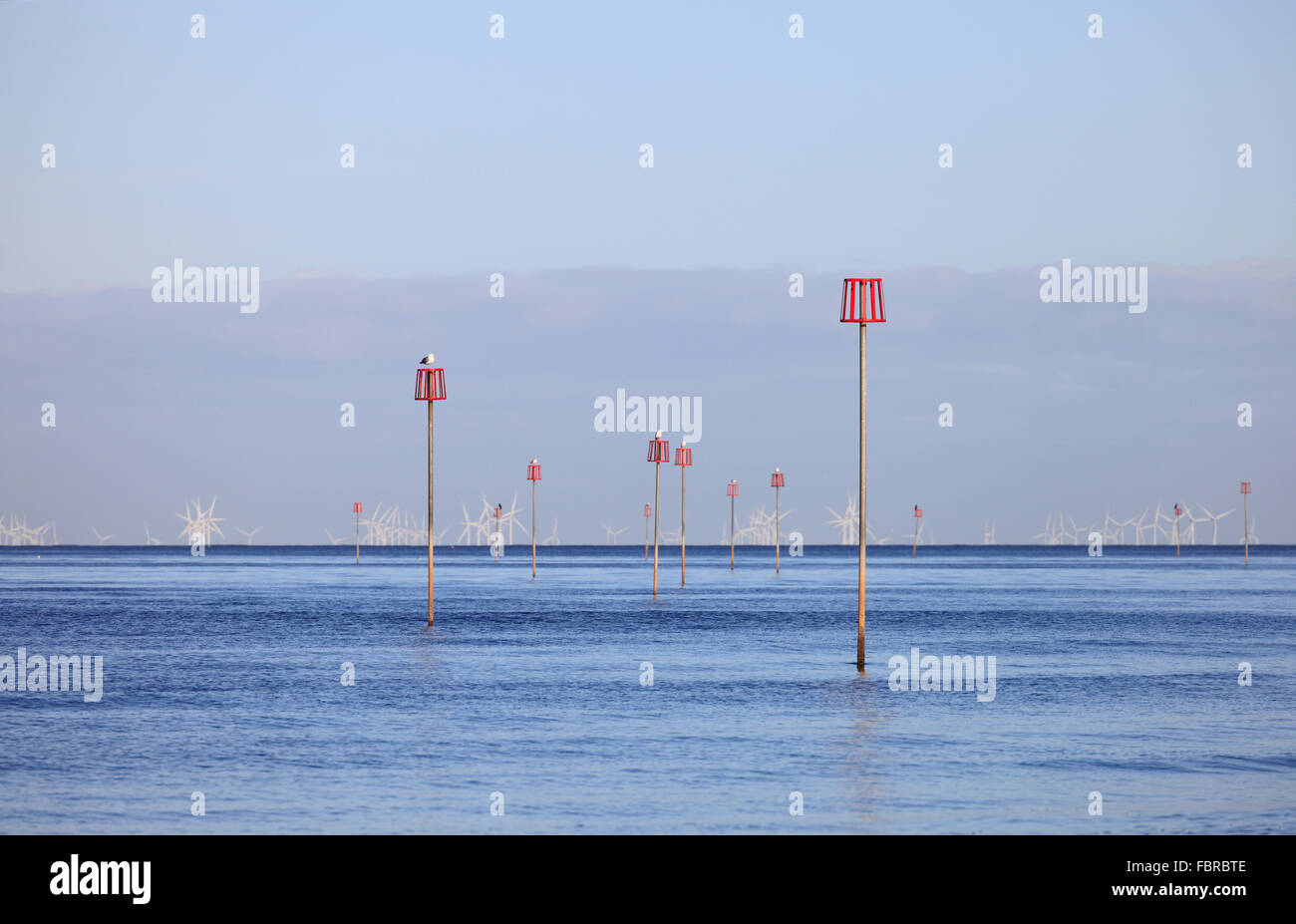 Marker für getauchten Buhnen und Windkraftanlagen in einem ruhigen blauen Meer. Stockfoto