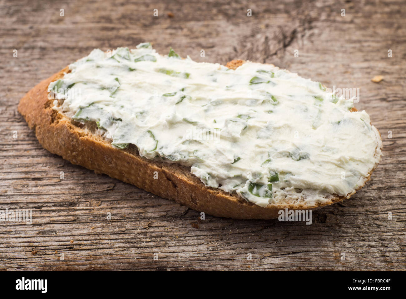 Kleines Sandwich mit cremiger Käse auf geschnittenem Brot auf hölzernen Hintergrund. Makro-Bild Stockfoto