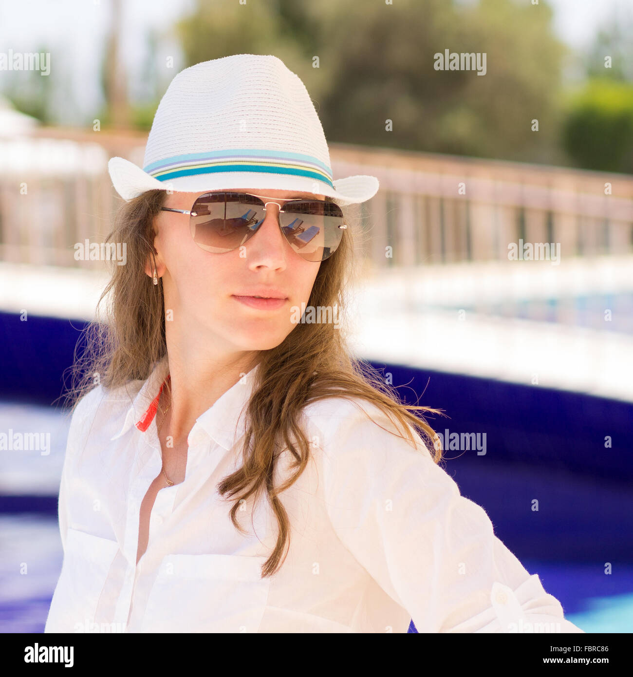 Junges schönes Mädchen steht neben dem Pool. Hübsche Frau im Sommerurlaub im tropischen resort Stockfoto