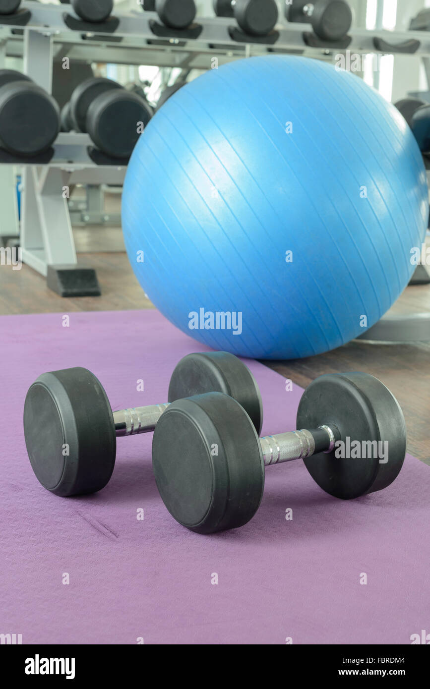 Es gibt Geräte für Fitnessstudio. (z. B. Kautschuk Hanteln, Yoga-Ball und Yoga-Matte) Stockfoto