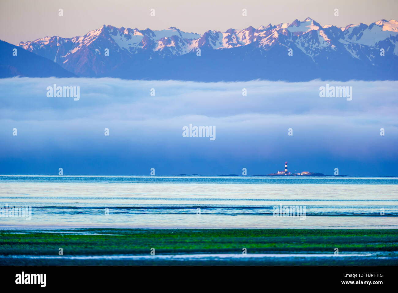 Rennen Sie, Felsen Leuchtturm und Olympic Mountains gesehen von Witty Lagune auf Vancouver Island, Kanada Stockfoto