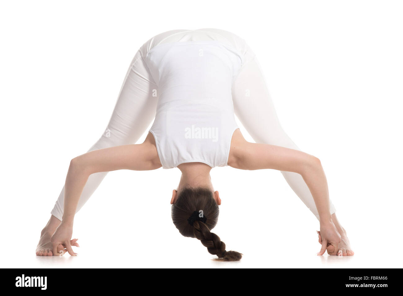 Sportlich schöne junge Frau in weißen Sportbekleidung stehend Straddle nach vorne beugen, Prasarita Padottanasana Haltung zu tun Stockfoto