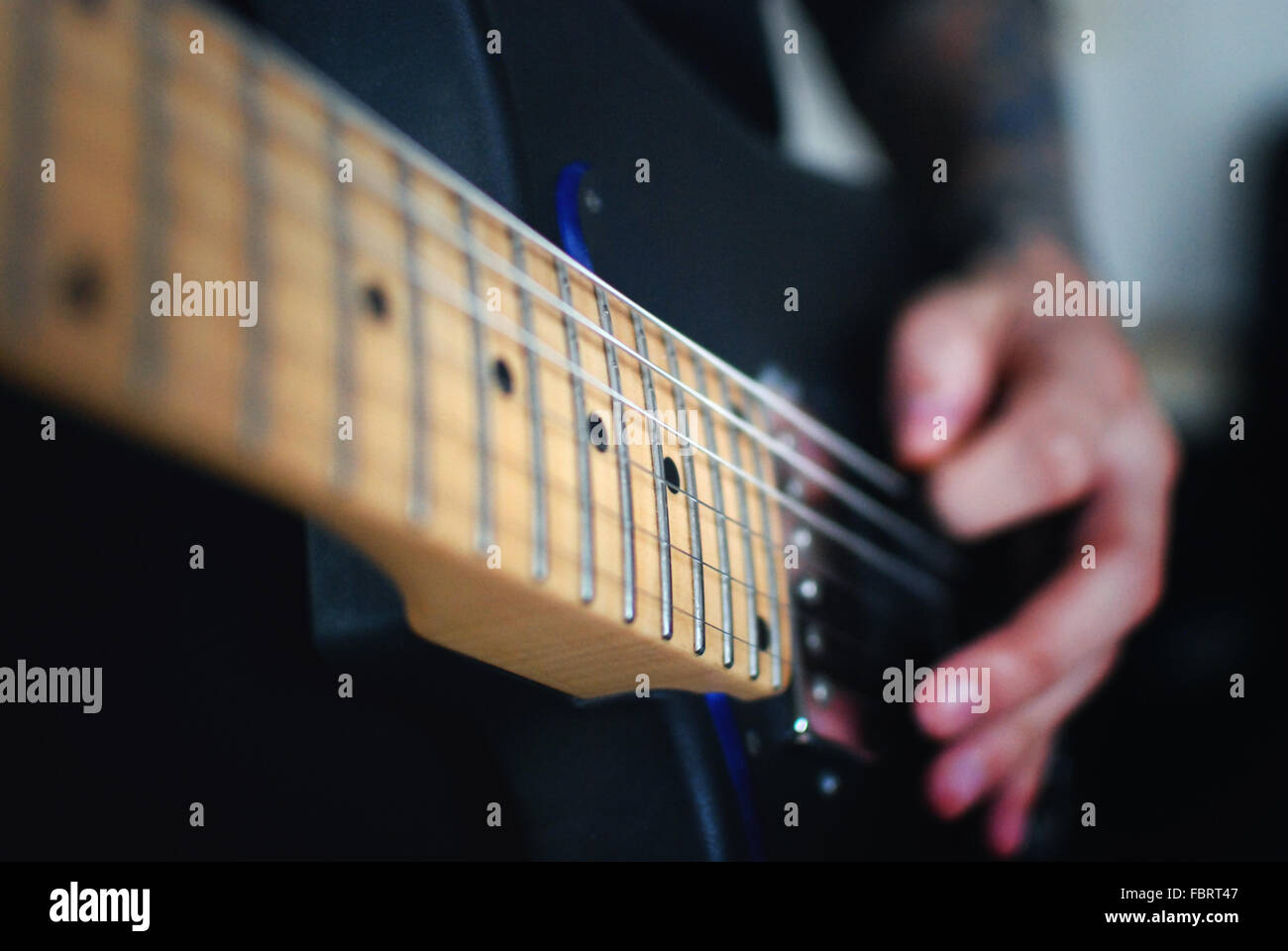 Beschriftung des jungen Musikers Gitarre zu spielen. Saiten der Gitarre können Biene gesehen und die Rückseite Plan ist verschwommen Stockfoto