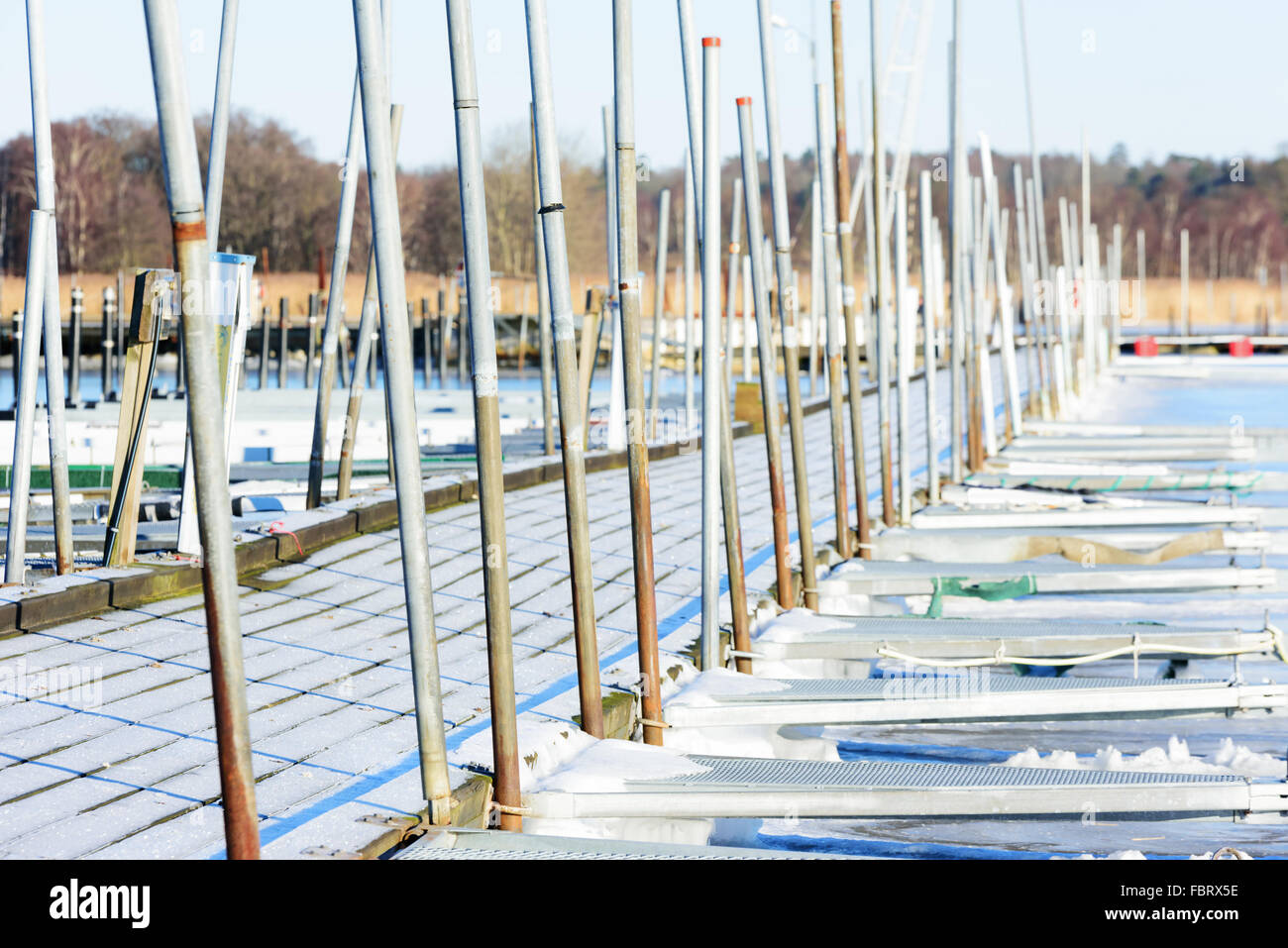 Ein Pier in einem Hafen im Winter. Der Holzboden ist frostig und es gibt keine Boote in der Marina. Viele Metall Polen stehen errichtet Stockfoto