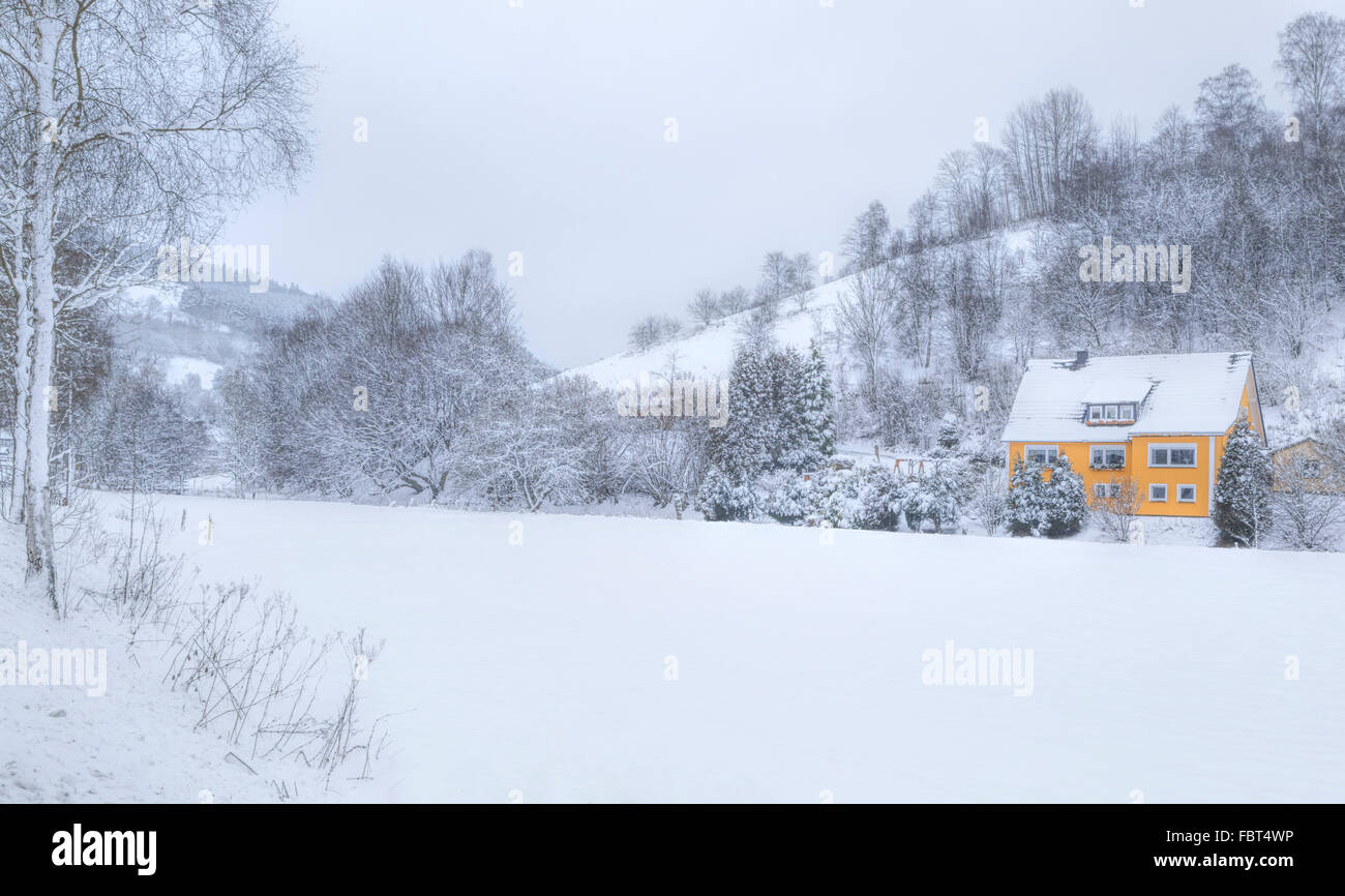 Ein gelbes Häuschen in ein Winterwunderland, Girkhausen, Bad Berleburg, im Sauerland, Nordrhein-Westfalen, Deutschland. Stockfoto