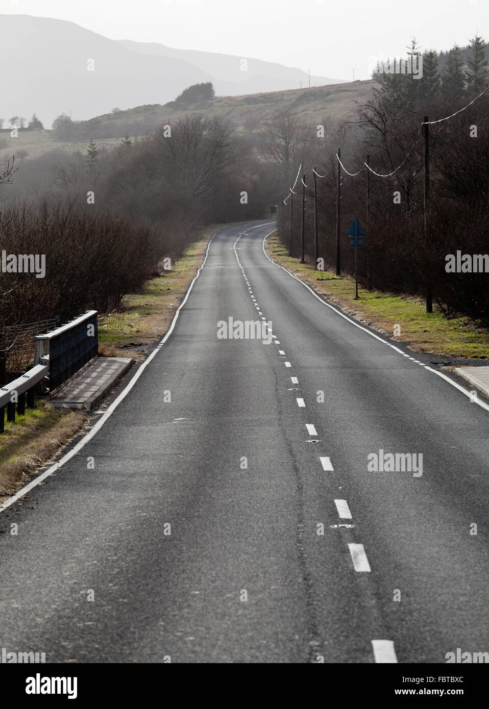 Eine einspurigen Straße führt in die Ferne zwischen Hügeln und Wiesen Stockfoto