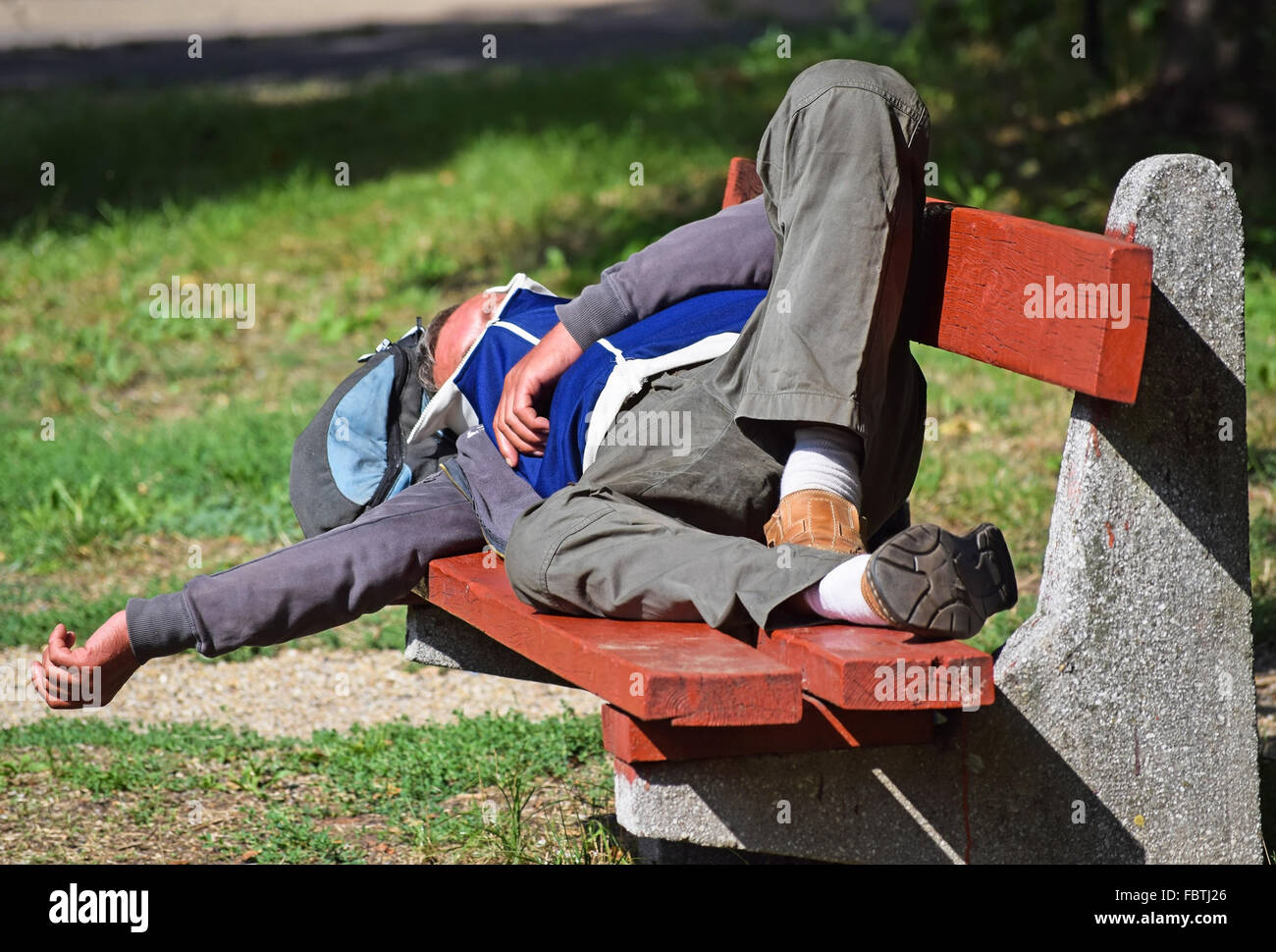 Obdachloser schläft auf einer Parkbank in der Stadt Stockfoto