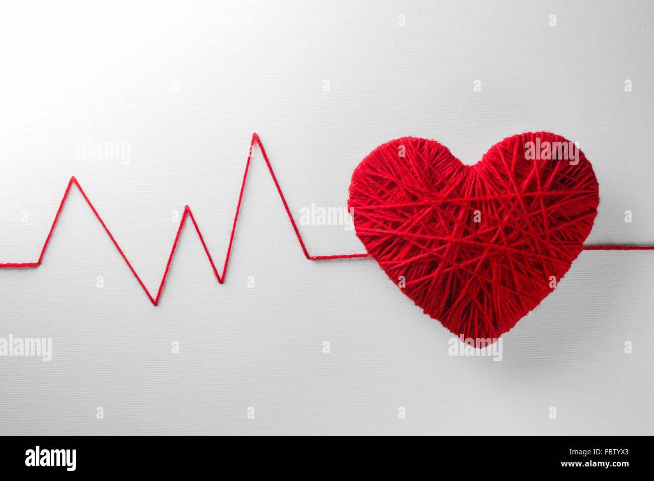Rotes Herz aus Wolle auf strukturierten weißen Hintergrund gemacht Stockfoto
