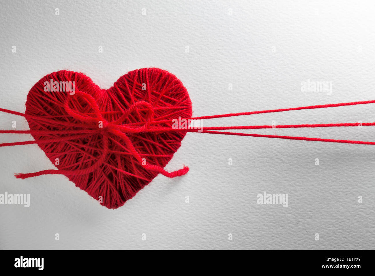 Rotes Herz aus Wolle auf strukturierten weißen Hintergrund gemacht Stockfoto