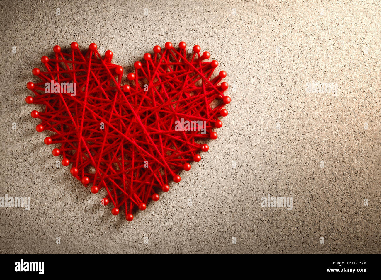 Rotes Herz aus Wolle gefertigt festgesteckt Pinnwand, Valentinstag-Konzept. Stockfoto