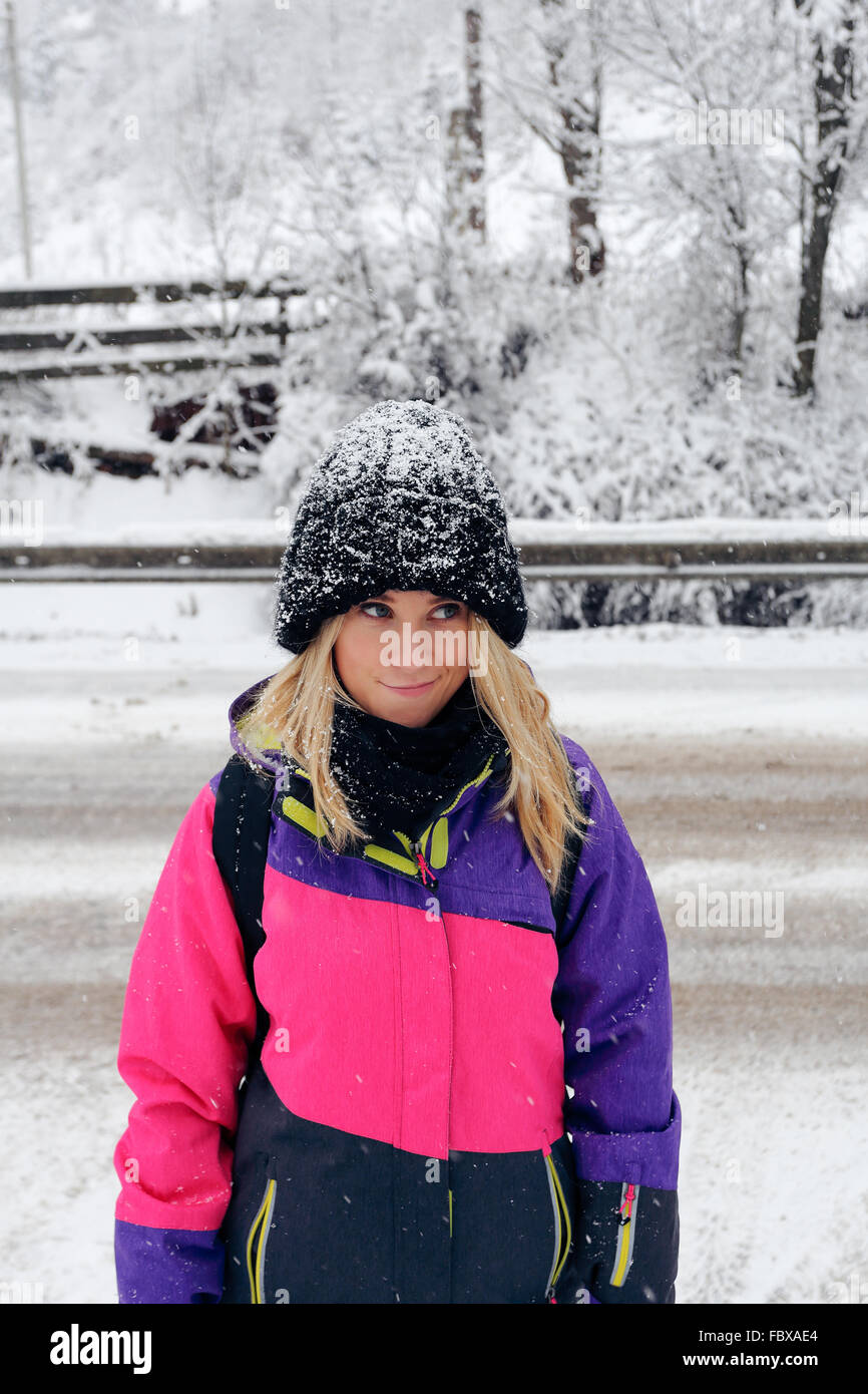 Lächelndes Mädchen in rosa Ski-Jacke und Hut mit Schnee Stockfoto