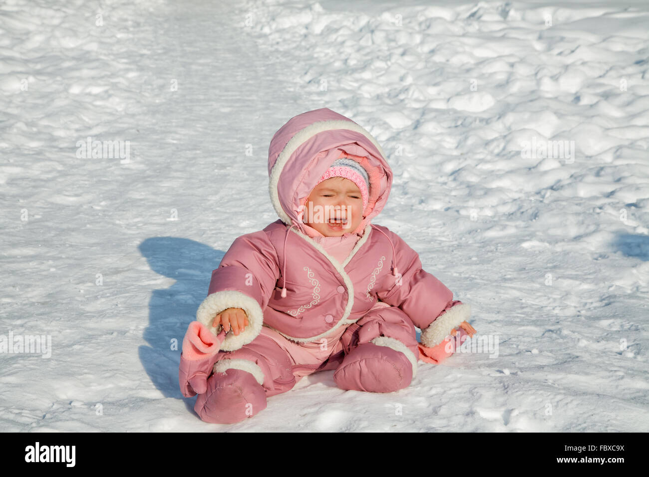 Das kleine Mädchen weint sitzen auf Schnee Stockfoto