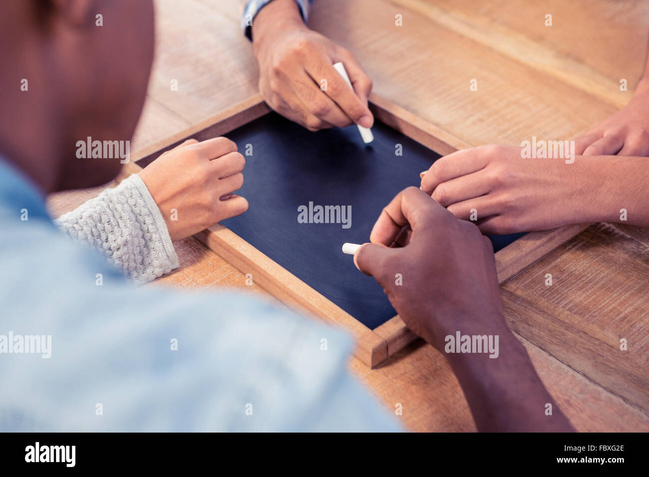 Hände von Geschäftsleuten schreiben auf Schiefertafel am Schreibtisch beschnitten Stockfoto