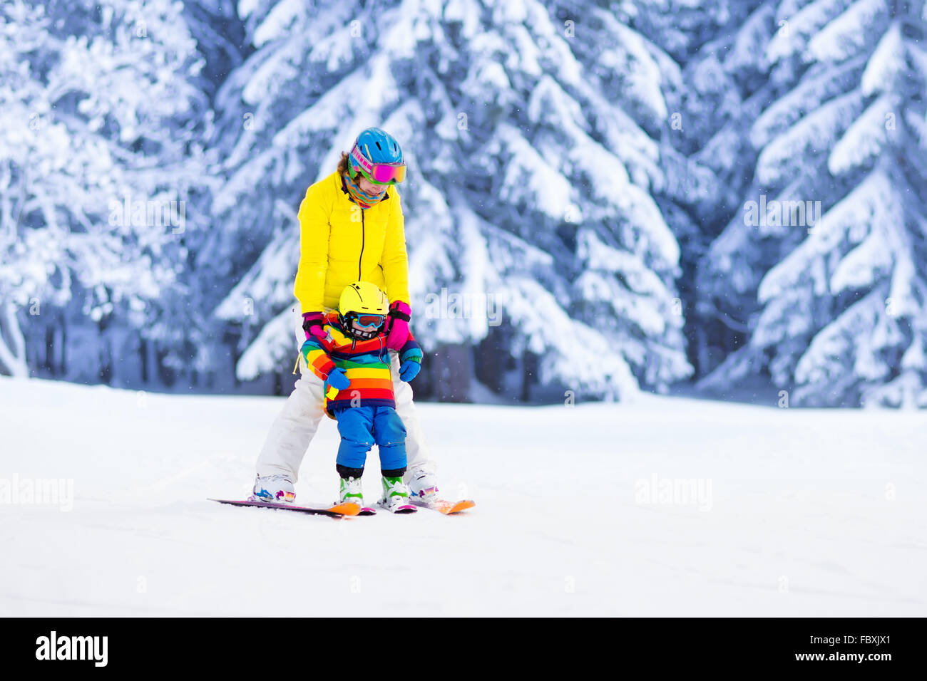 Mutter und Kind Skifahren in den Alpen. Aktive Mutter und Kleinkind Kind mit Helm, Schutzbrille und Polen. Skikurs Stockfoto