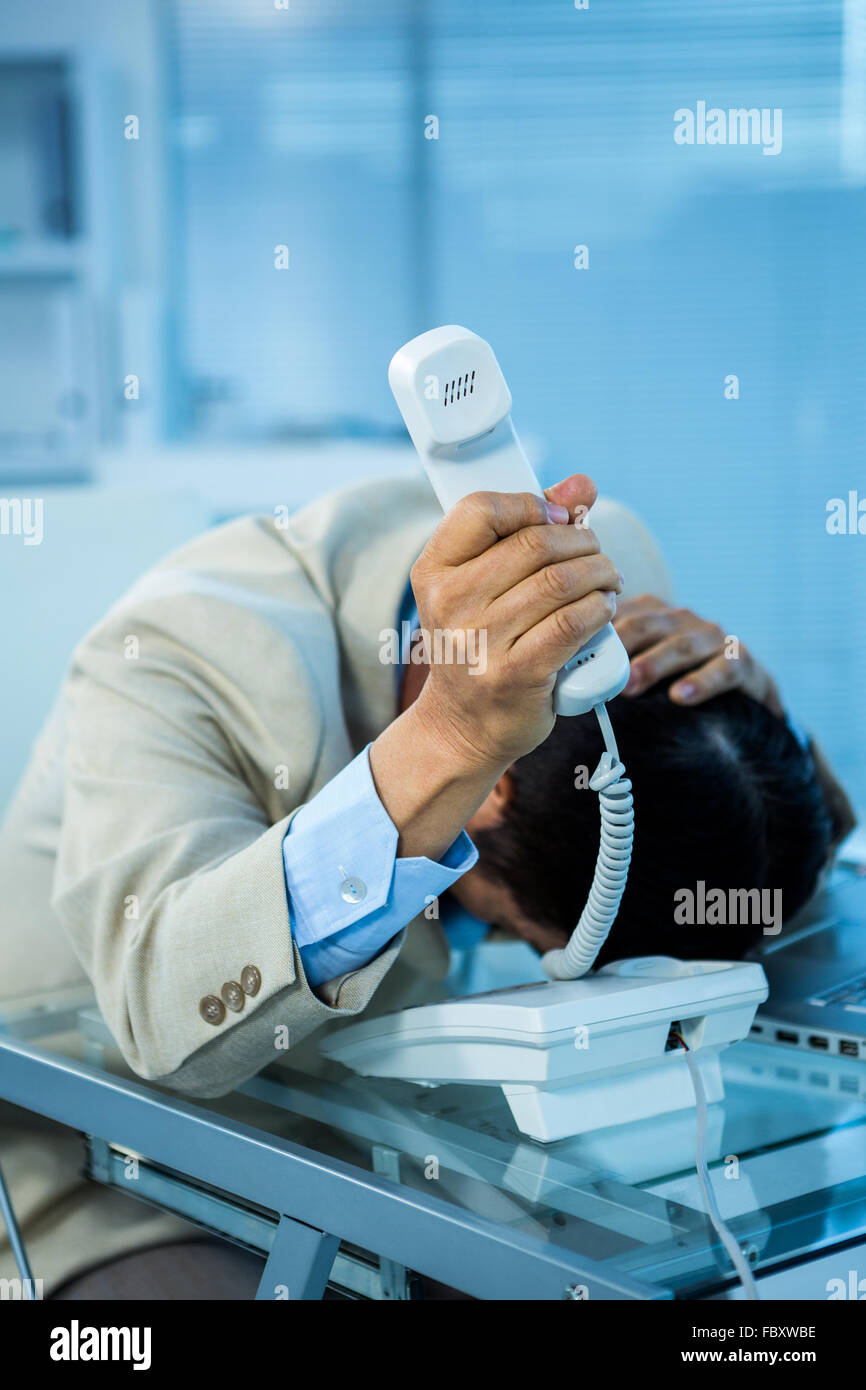 Überwältigt asiatischen Geschäftsmann ans Telefon Stockfoto