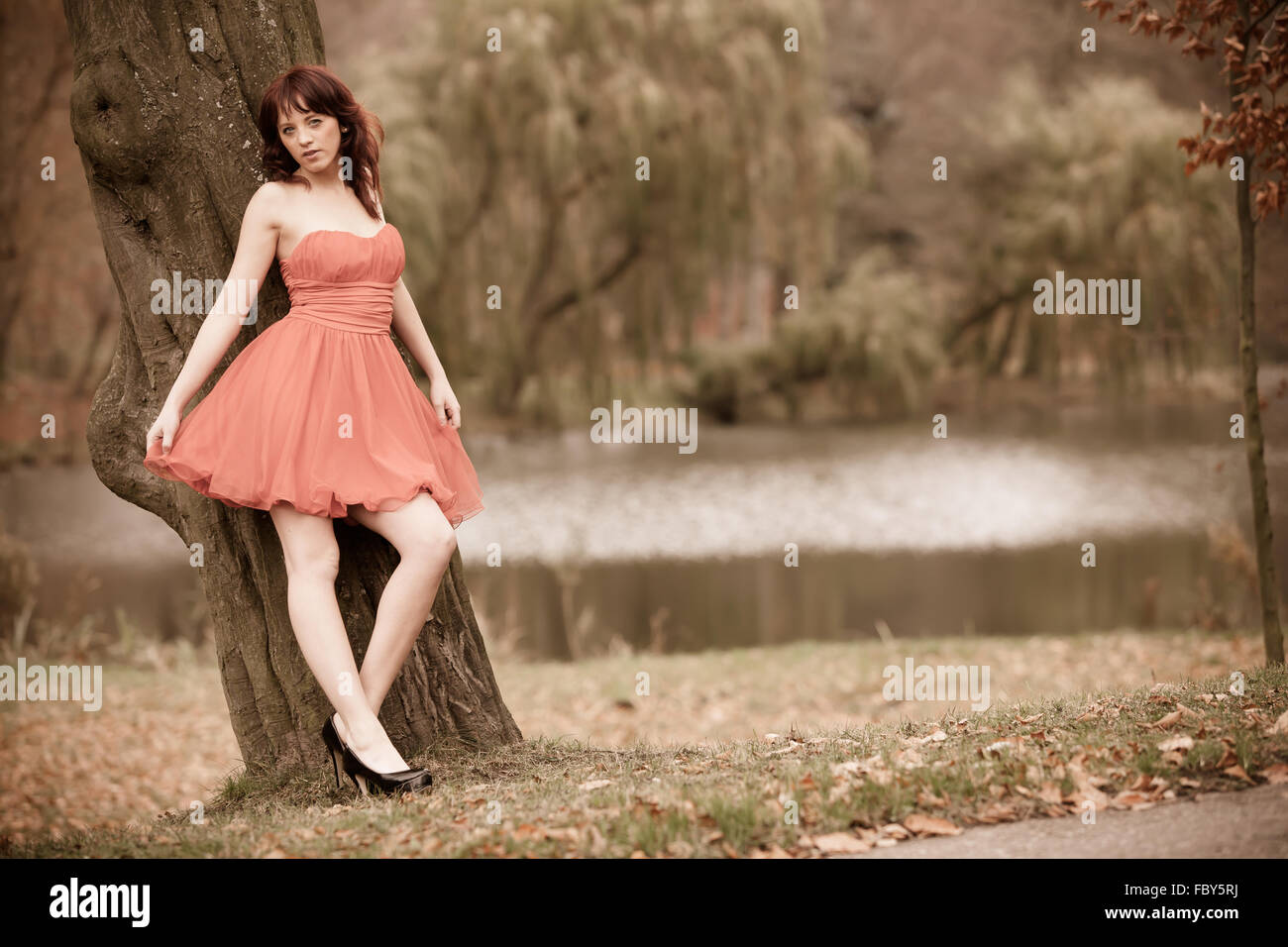 Mode junge Frau im roten Kleid Entspannung im park Stockfoto