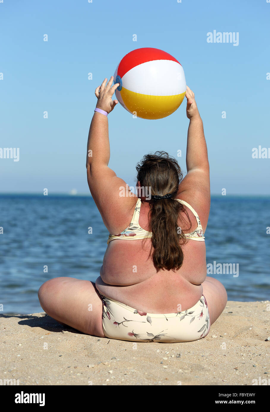 übergewichtige Frau Turnen am Strand Stockfoto
