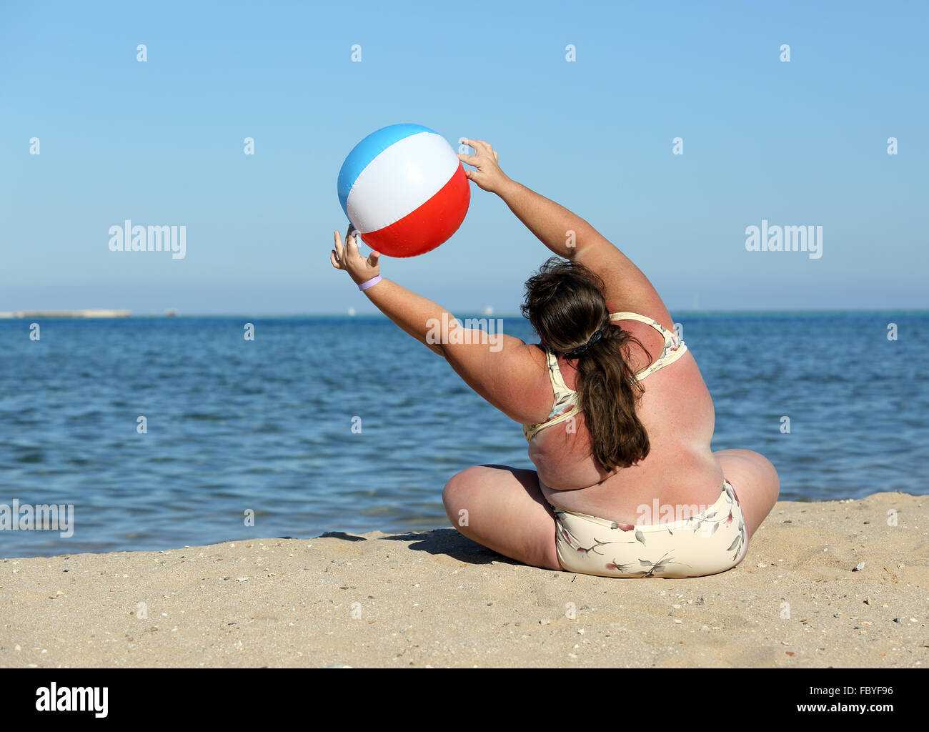 übergewichtige Frau Turnen am Strand Stockfoto
