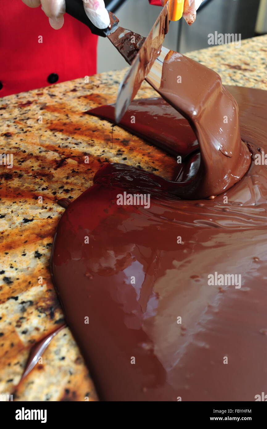 Essen Süßigkeiten Schokolade macht Frau Temperieren von Schokolade auf einem kalten Marmor Tisch Stockfoto