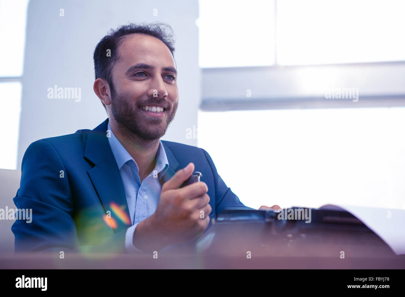 Glücklich Kaufmann wegsehen beim Sitzen im Büro Stockfoto