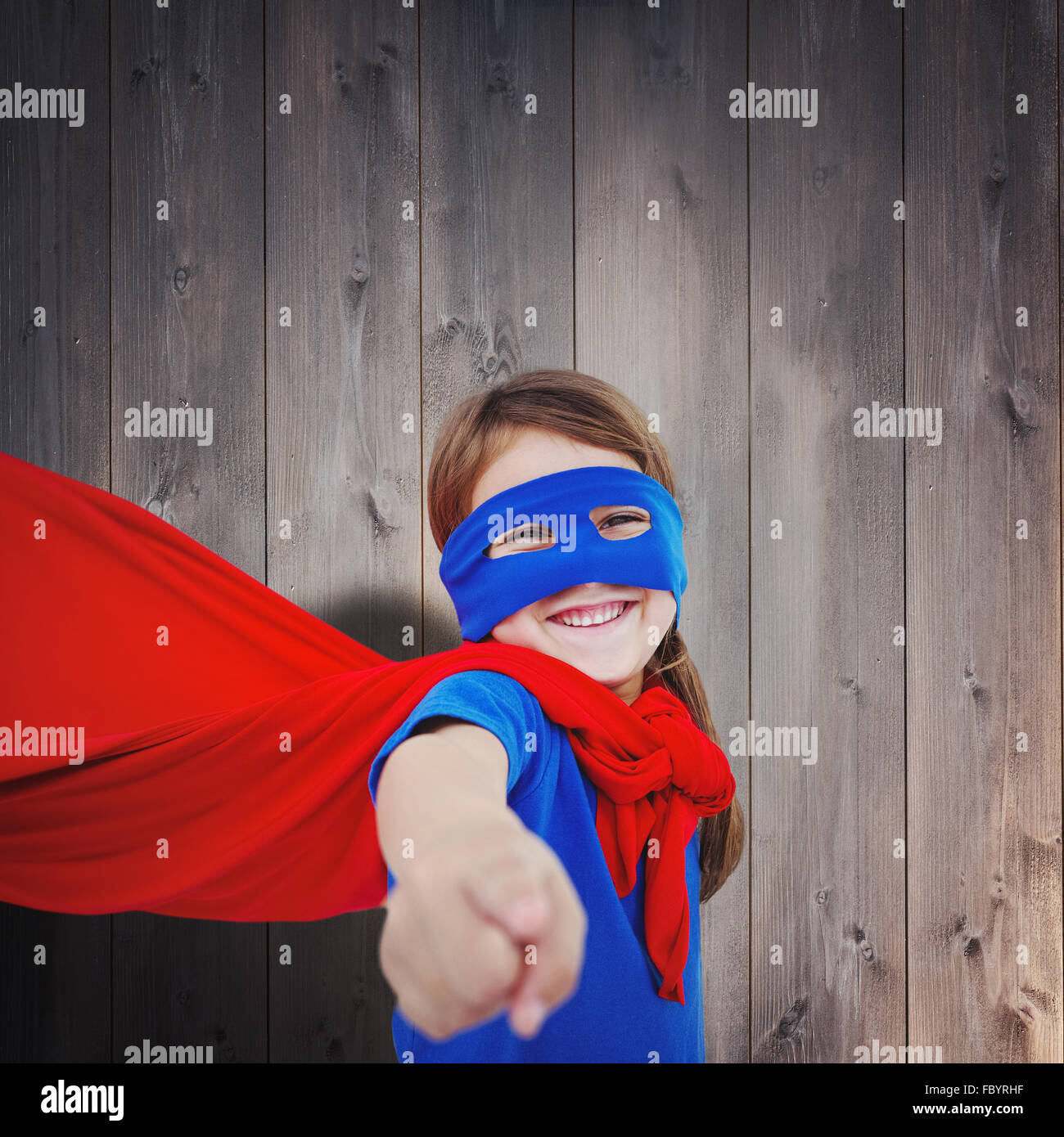 Zusammengesetztes Bild des lächelnden maskierten Mädchen vorgibt, Superheld zu werden Stockfoto