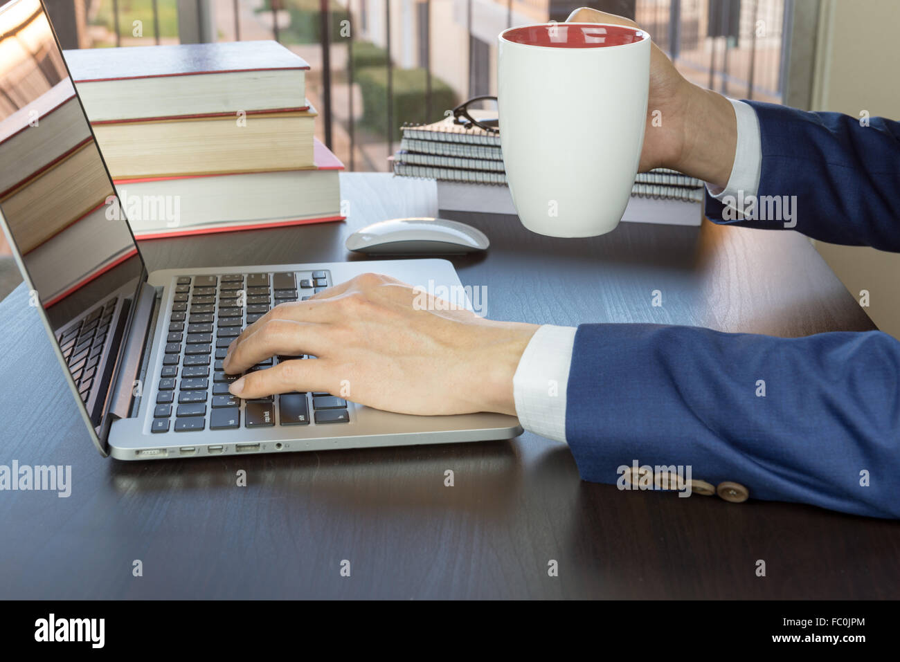 Mann im Anzug arbeiten im Büro-Schreibtisch, Grabing Tasse Kaffee Stockfoto