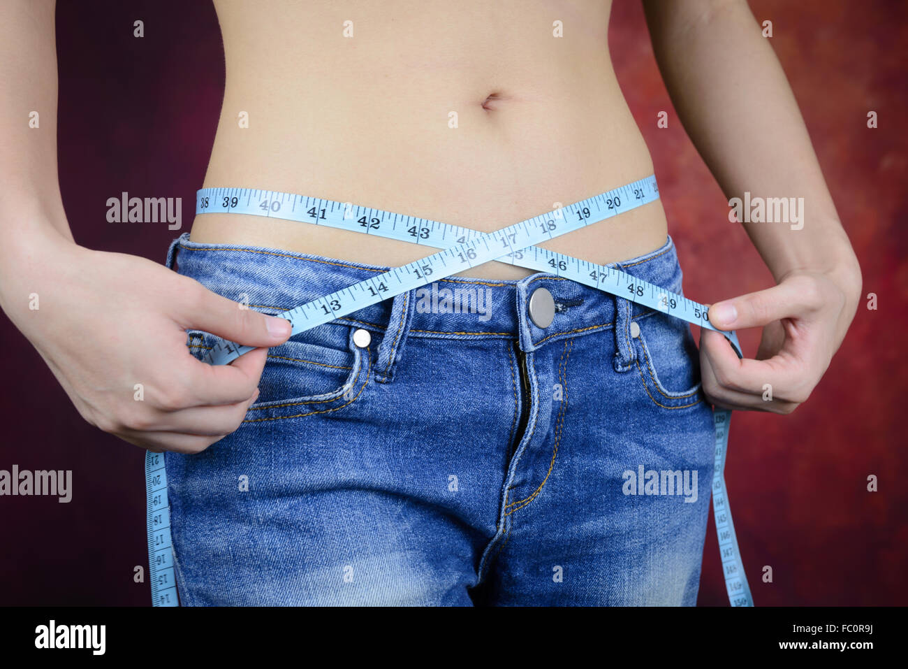 schlanke Asiatin, trägt Jeans, messen ihre Körperform, Taille, Gesäß Stockfoto