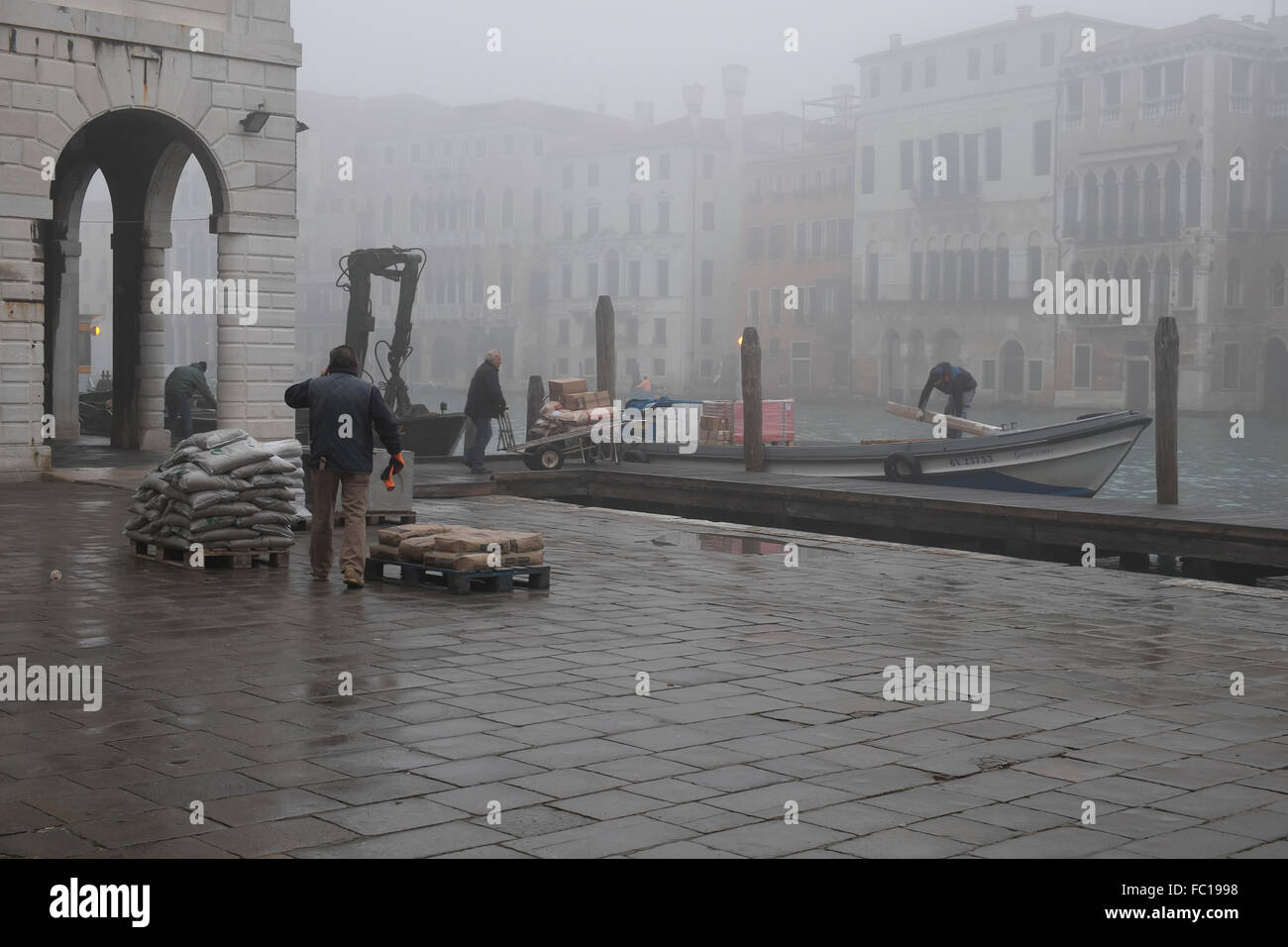 Arbeiter entladen waren von einem Boot vertäut am Canal Grande in Venedig Stockfoto