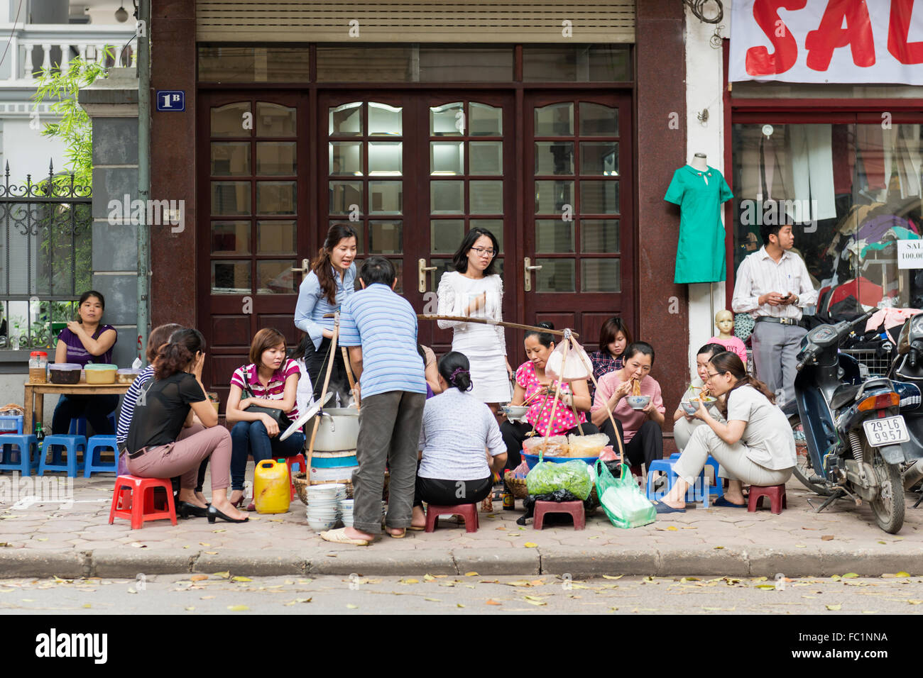 Frauen Essen an einem Straßenstand in der Nha Tho Gegend von Hanoi, Vietnam Stockfoto