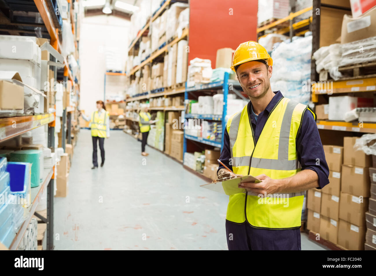 Lagerarbeiter, lächelnd in die Kamera mit Zwischenablage Stockfoto