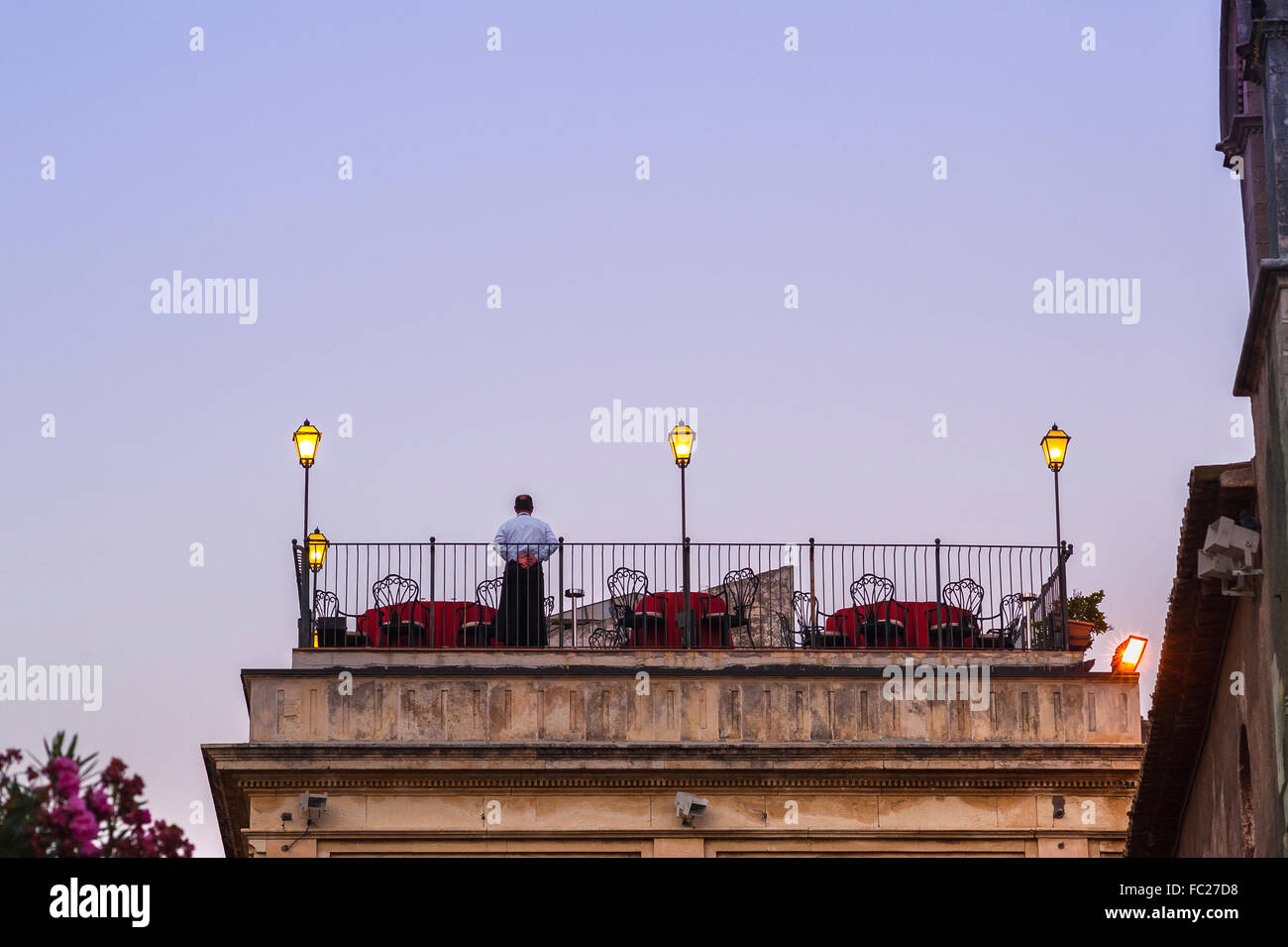 Restaurant auf der Dachterrasse, ein einsamer Kellner steht für Abend Diners bereit an einer Dachterrasse auf ein Restaurant in Taormina, Sizilien zu gelangen. Stockfoto