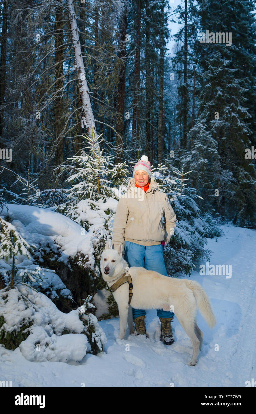 Frau mit Hund im Winterwald spazieren Stockfoto