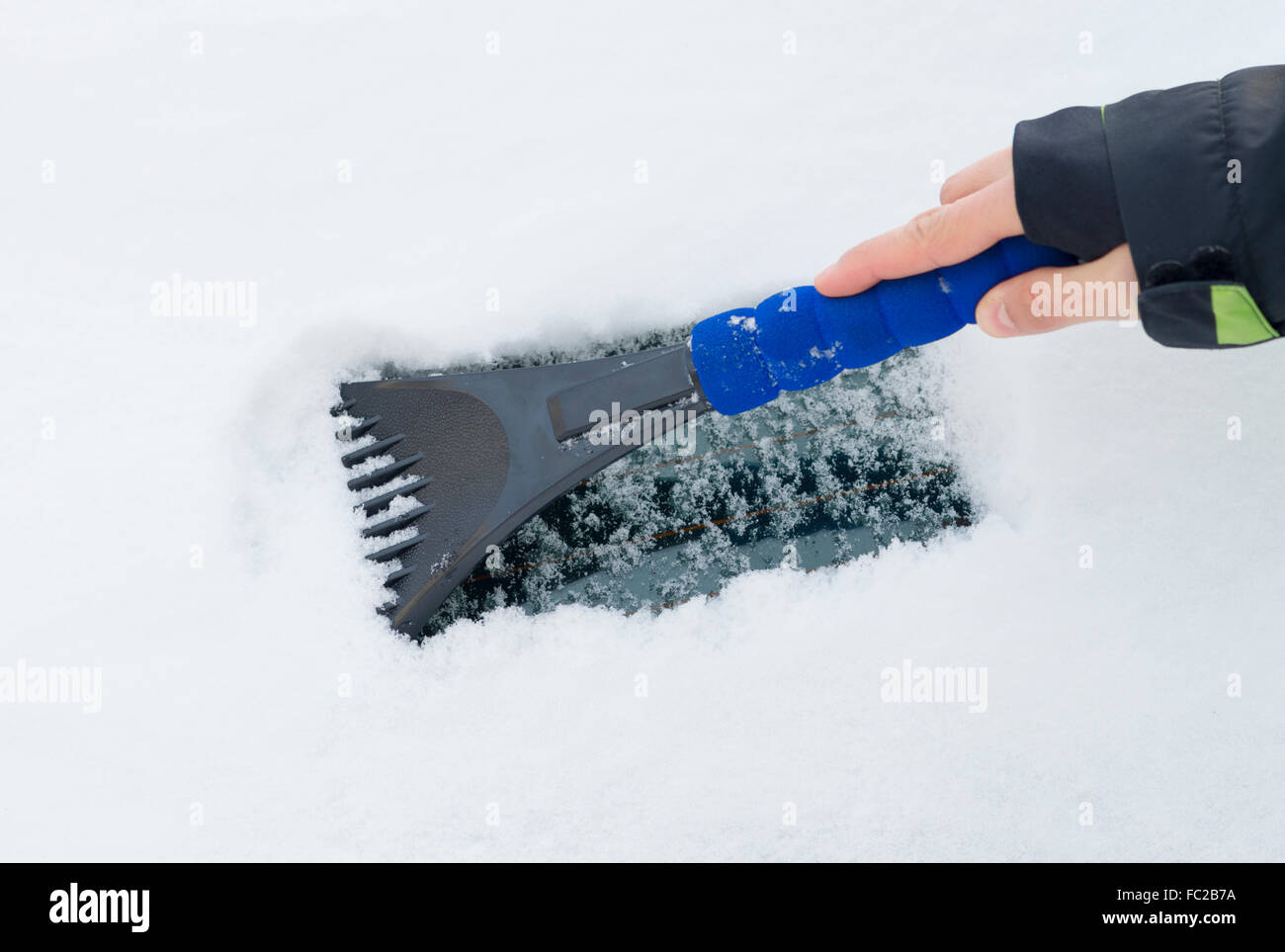 Reinigung der Windschutzscheibe von Schnee durch Eiskratzer mit Bürste im  Winter. Schnee vom Auto auf der Straße entfernen Stockfotografie - Alamy