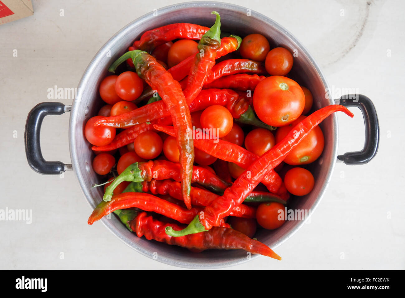 Topf voll rote Tomaten und roten Chilischoten. Stockfoto