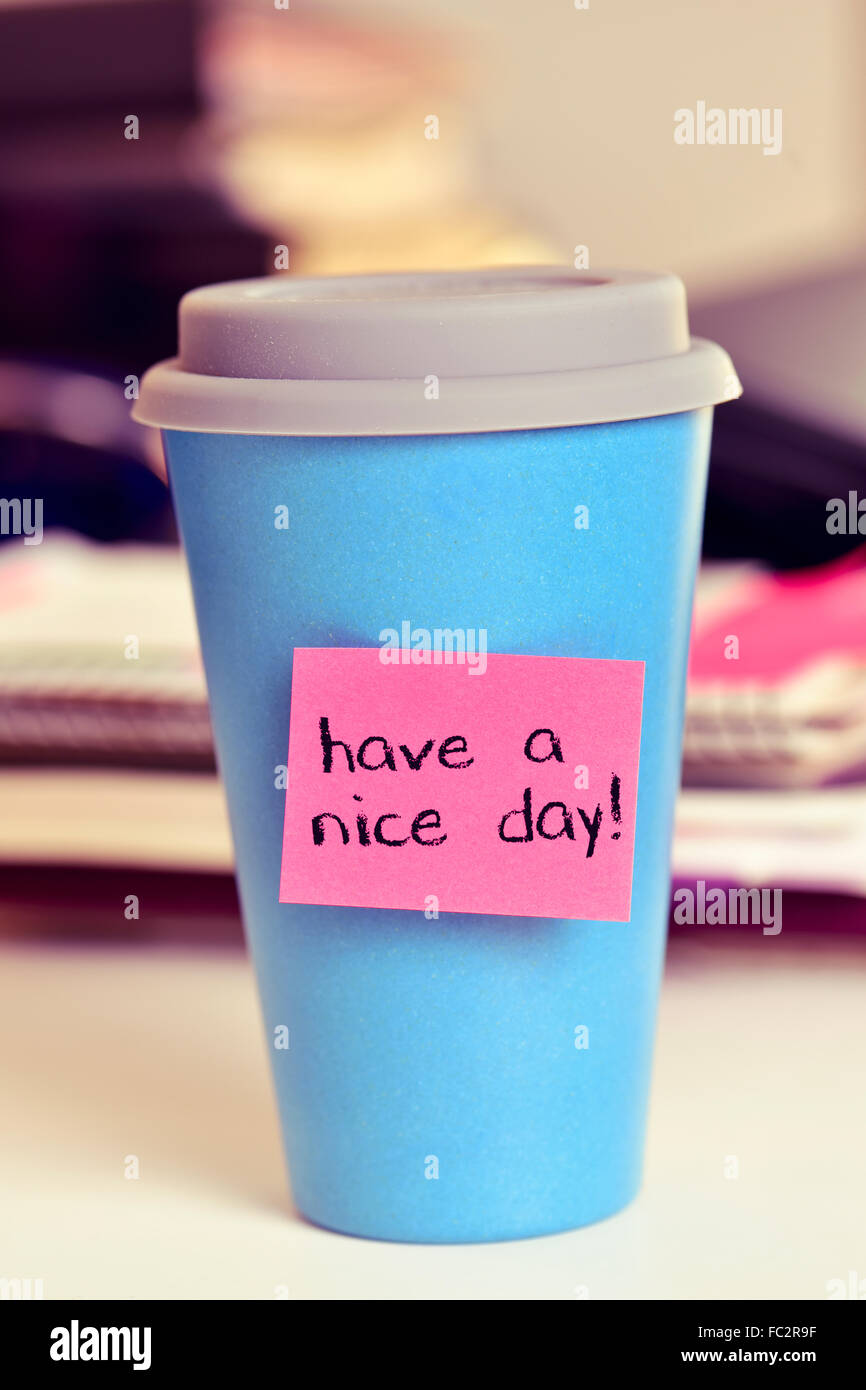 eine rosa Notiz mit dem Text noch einen schönen Tag an einem blauen Tasse Kaffee oder Tee auf einem Schreibtisch befestigt Stockfoto