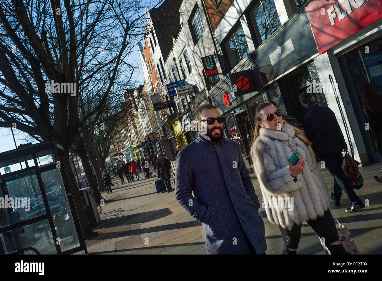 Islington, London, England. Januar 2016 Mann und Frau im trendigen Islington in North East London zu Fuß auf einem hellen Wintertag. Frau trägt Pelz, Mann tragen intelligente Mantel und Sonnenbrille. Stockfoto