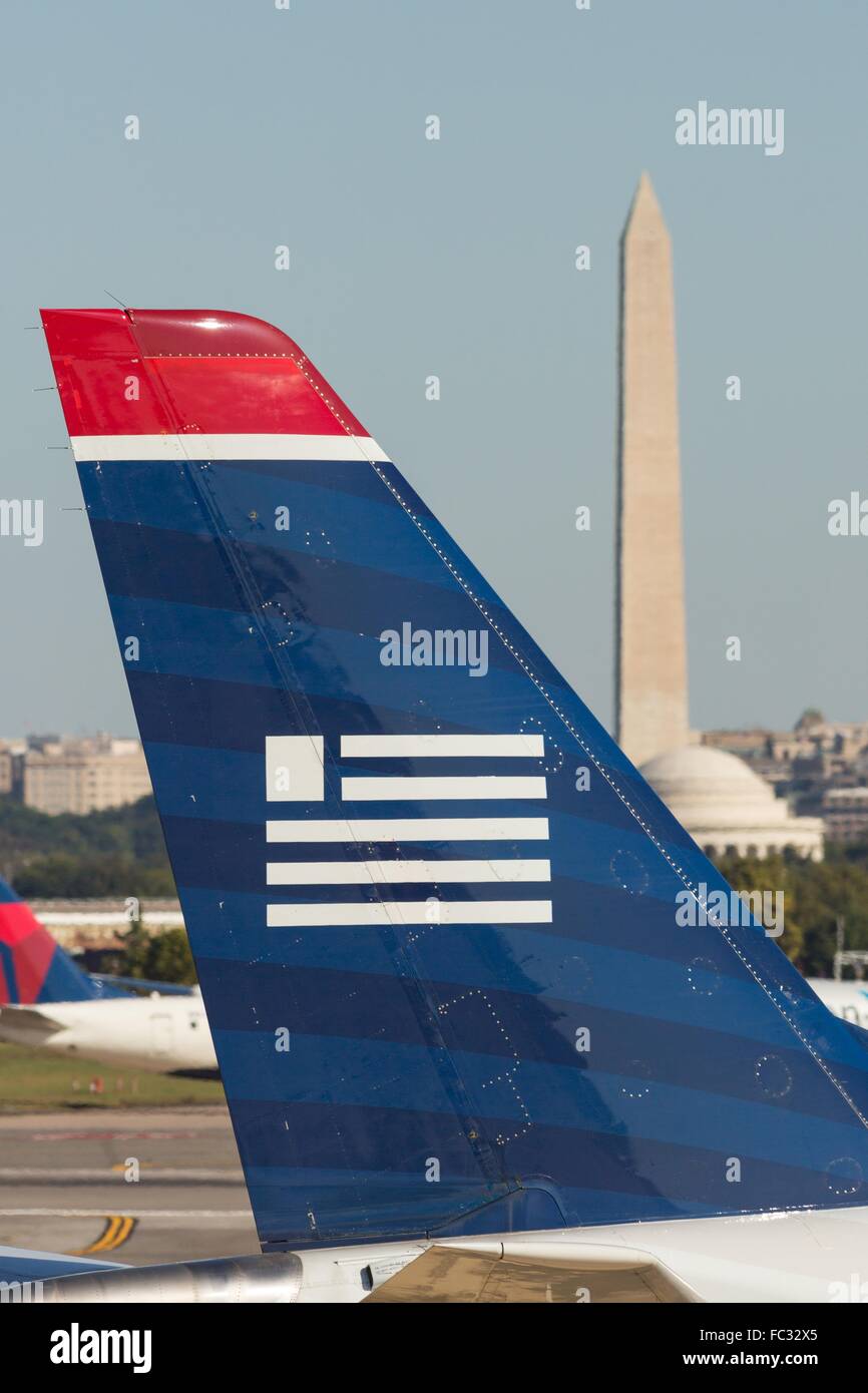 Die Schwanzflosse und das Logo eines US Airways Jets mit dem Washington Monument und dem Jefferson Memorial im Hintergrund an Reagan National Airport über den Potomac aus Washington während der Operationen 5. Oktober 2014 in Arlington, Virginia. Stockfoto