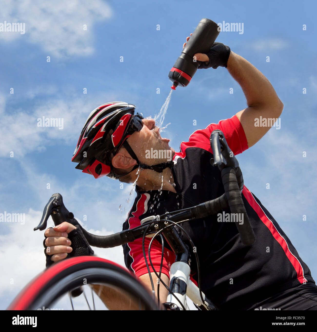 Radler erfrischt aus einer Flasche während der Fahrt mit dem Fahrrad Stockfoto