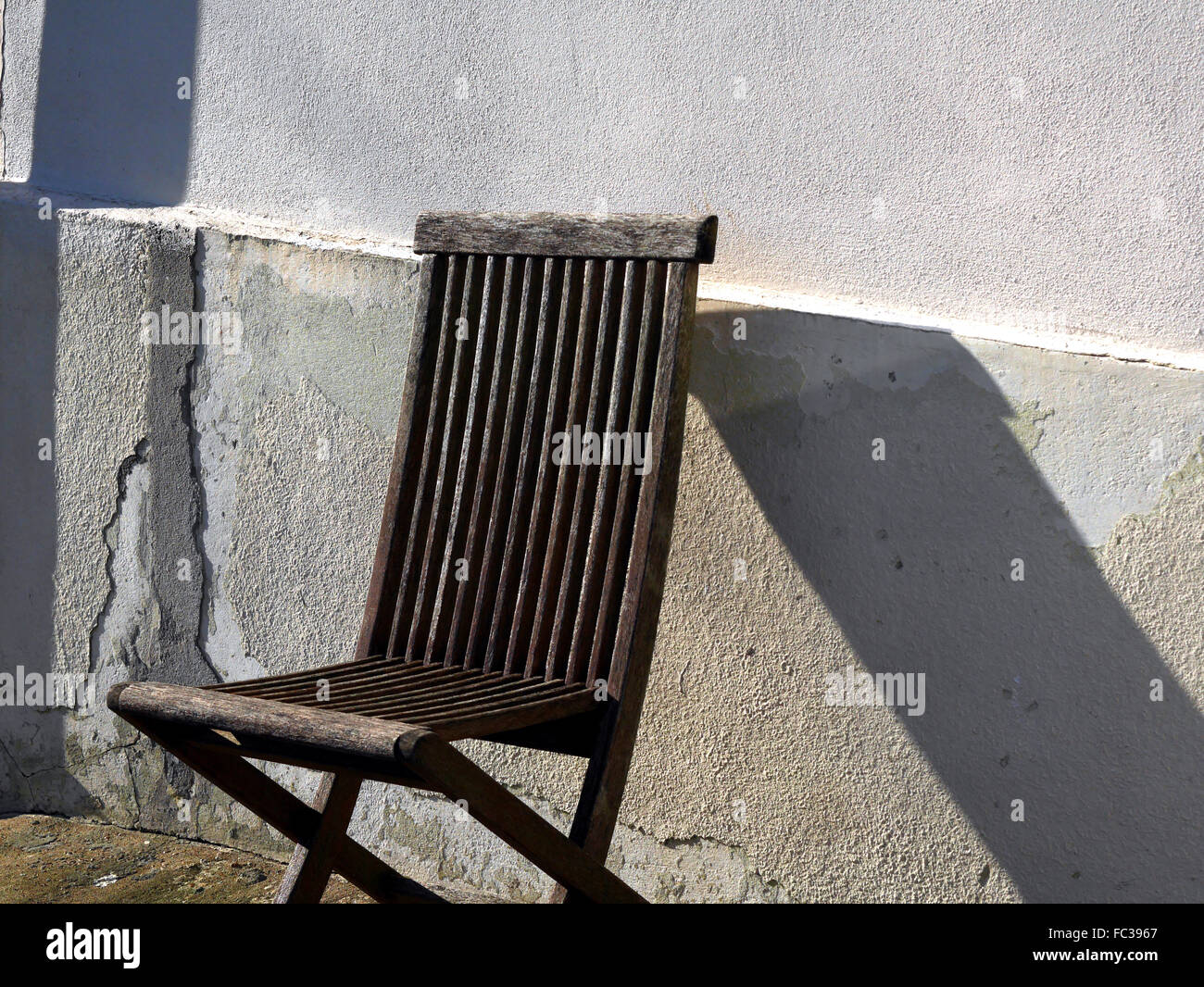 Einsame Holzstuhl mit Schatten an Wand Stockfoto